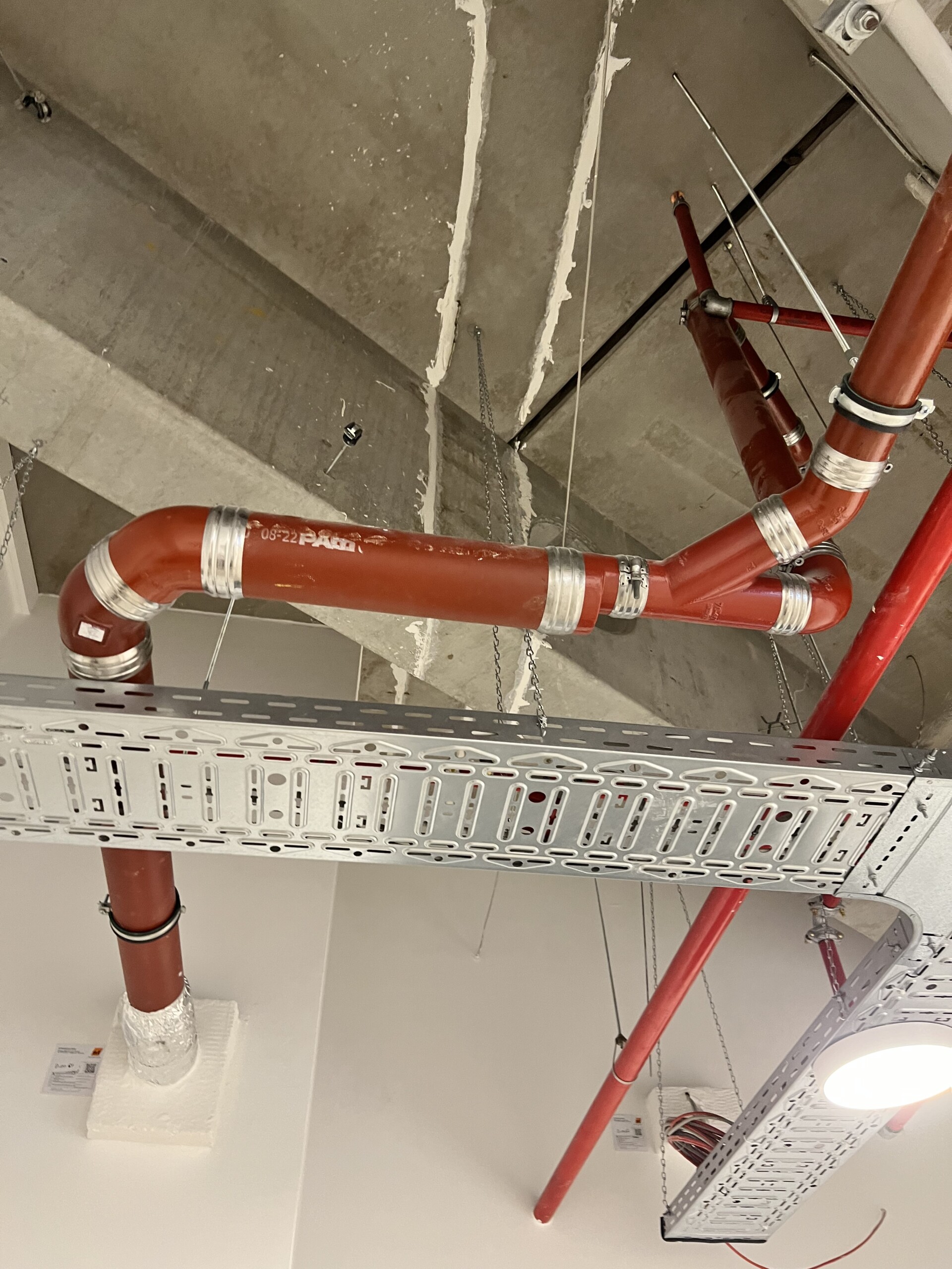 Abwasserrohre, Sprinkleranlage und Kabeltrasse an einer Decke
